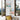 Two Italian art prints on a wall by an open window and chair, coastal town and domed cityscape.