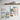 Two framed illustration art prints of London cityscape on a wall below a wooden shelf.