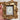 A hand holding a rectangular decorative gold frame with a small canvas print featuring blue flowers.