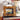 Decorative gold frame with a small painting on top of books, next to a floral-patterned vase.